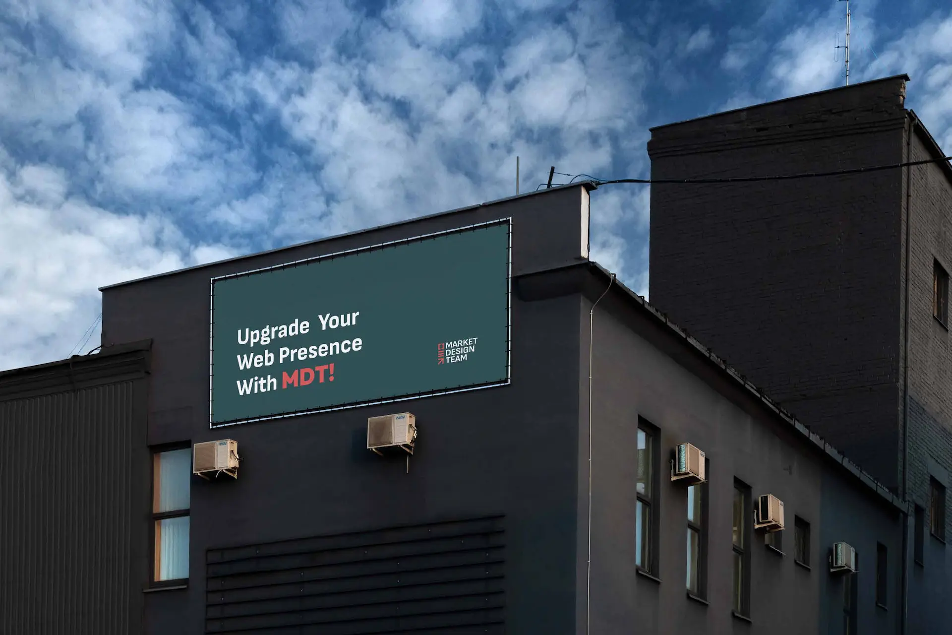 A billboard on a dark building against a cloudy sky reads, "Upgrade Your Web Presence With MDT!" in white and red text, alongside a logo. - Market Design Team: Define. Structure. Expand