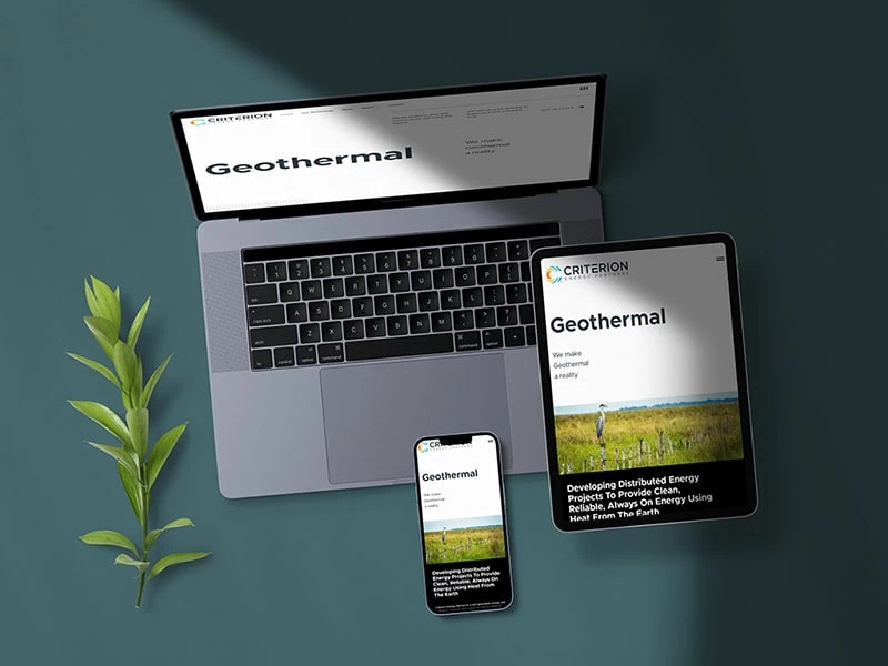 A laptop, tablet, and smartphone displaying the responsive Criterion website with the title "Geothermal" are laid out on a dark green surface. - Market Design Team: Define. Structure. Expand.