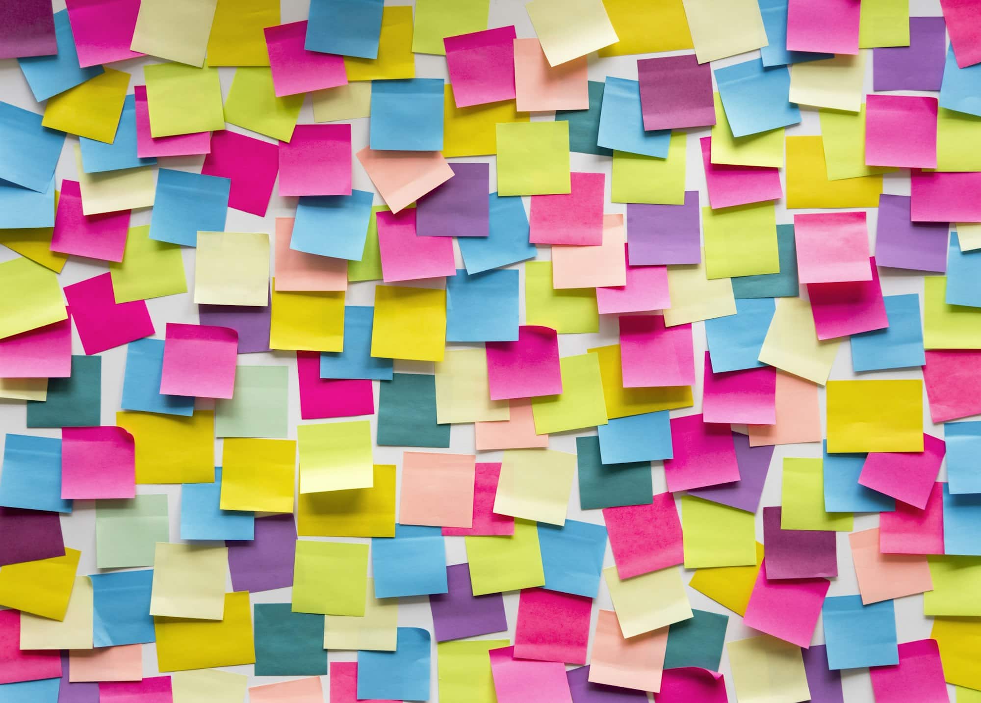 A large assortment of colorful sticky notes, are randomly arranged on a surface for small business planning. - Market Design Team: Define. Structure. Expand.