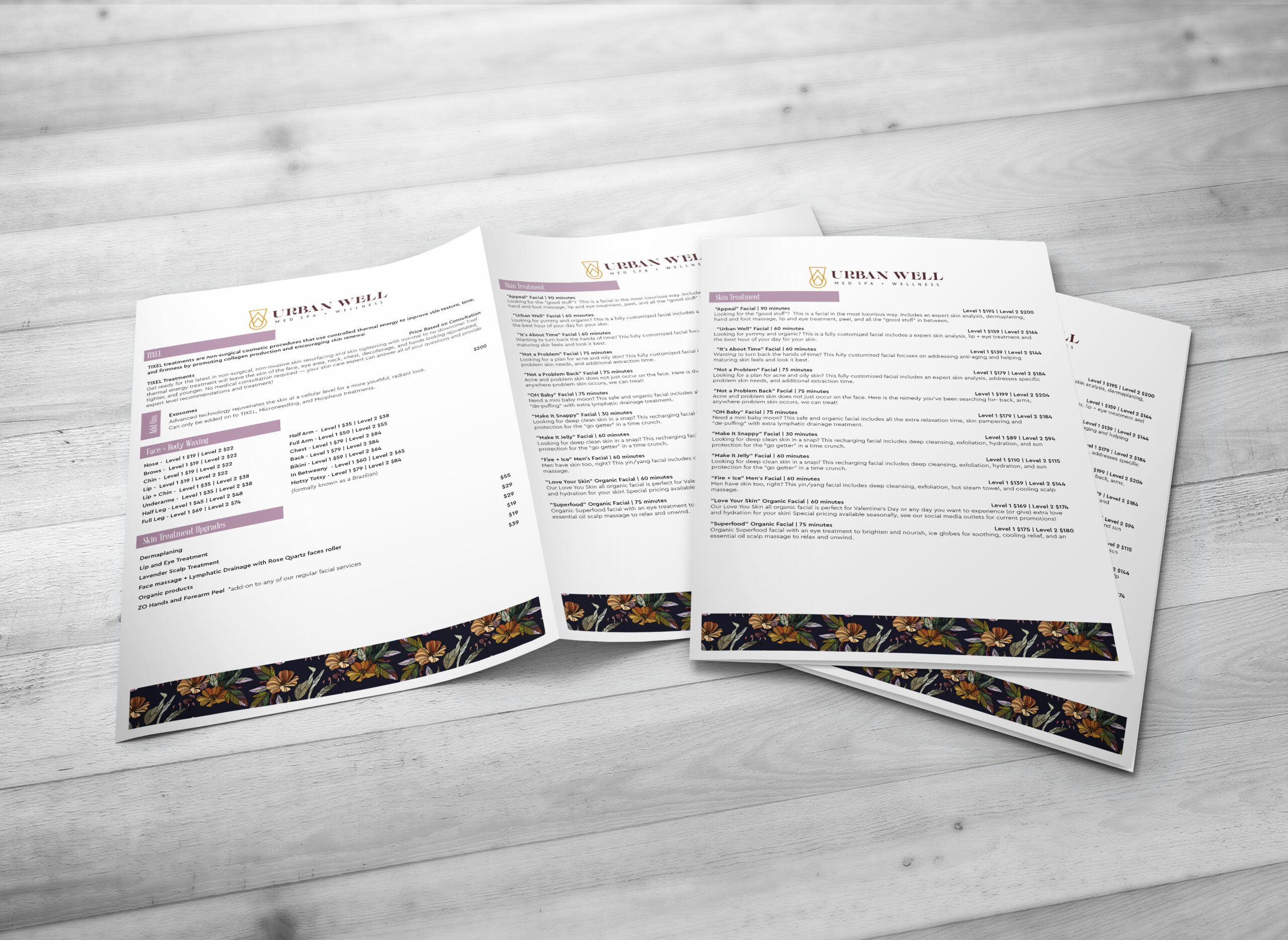 Three white menus with floral borders at the bottom are displayed on a light wooden surface. The menus are titled "Urban Well" and contain sections of text, headers, and prices in a clean, organized layout. - Market Design Team: Define. Structure. Expand.