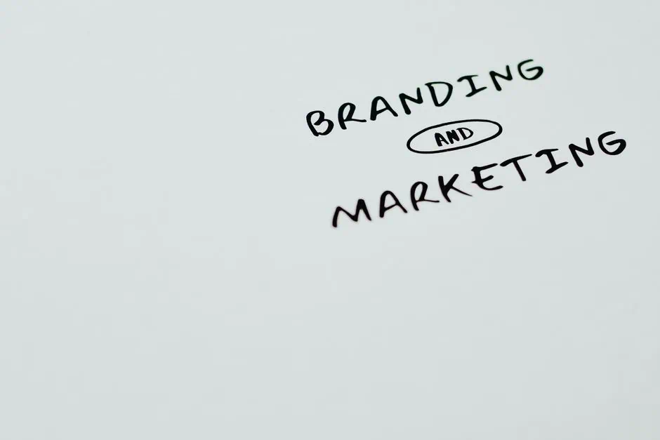 the image shows the words “branding and marketing” handwritten in black marker on a white background, with “and” circled. the words are positioned towards the upper right of the image, evoking the creative touch often seen from a top branding agency in southeast texas. market design team: define. structure. expand.