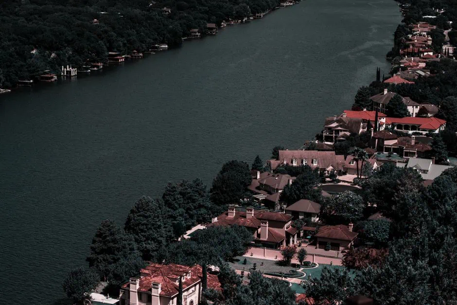 aerial view of a river bordered by densely clustered houses and trees in lake jackson, texas. the homes have various roof colors and the river curves along the landscape, with more wooded areas visible on the opposite bank—a scene as vibrant and unique as a custom website design. market design team: define. structure. expand.