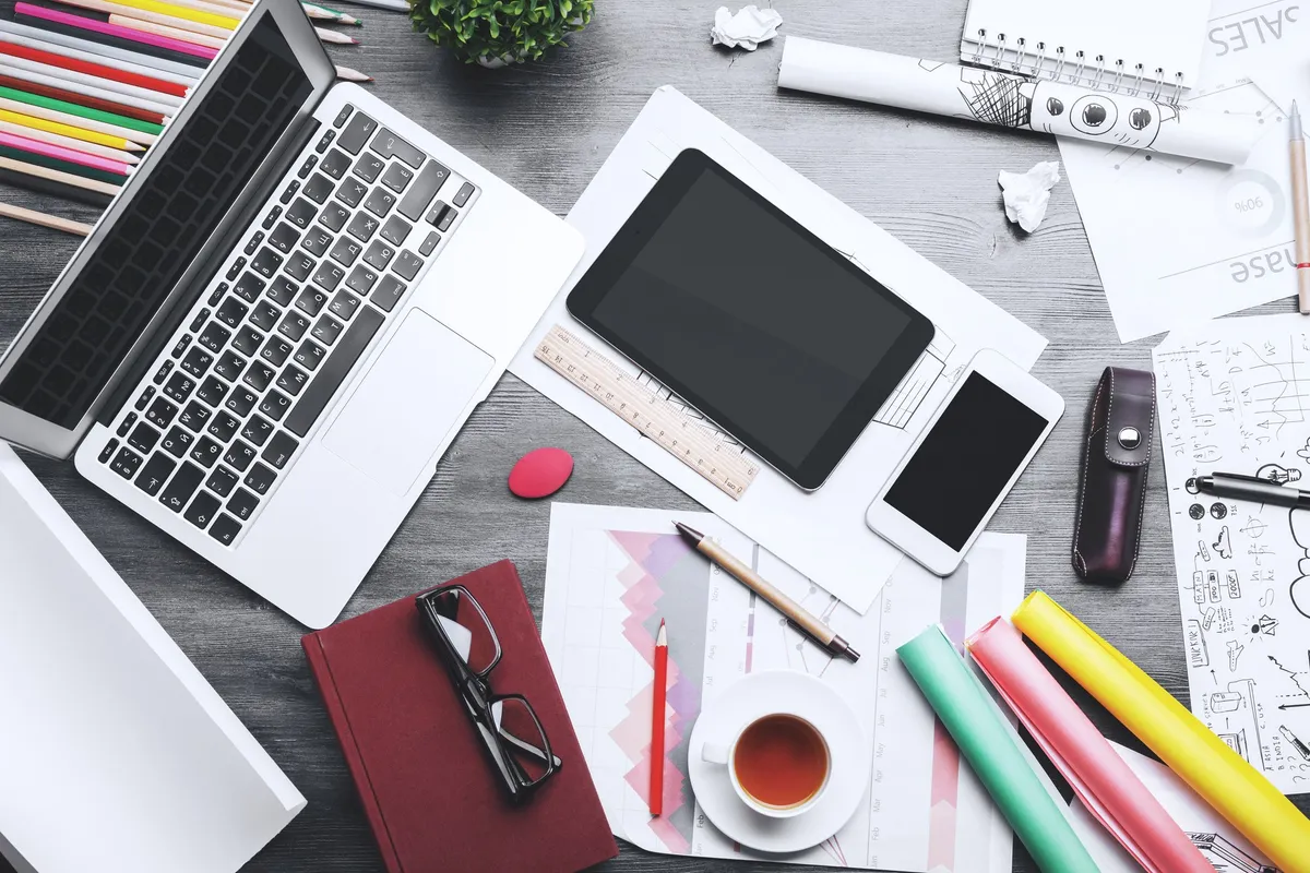 A creative, messy table filled with design tools and materials, reflecting the process of small business website design.