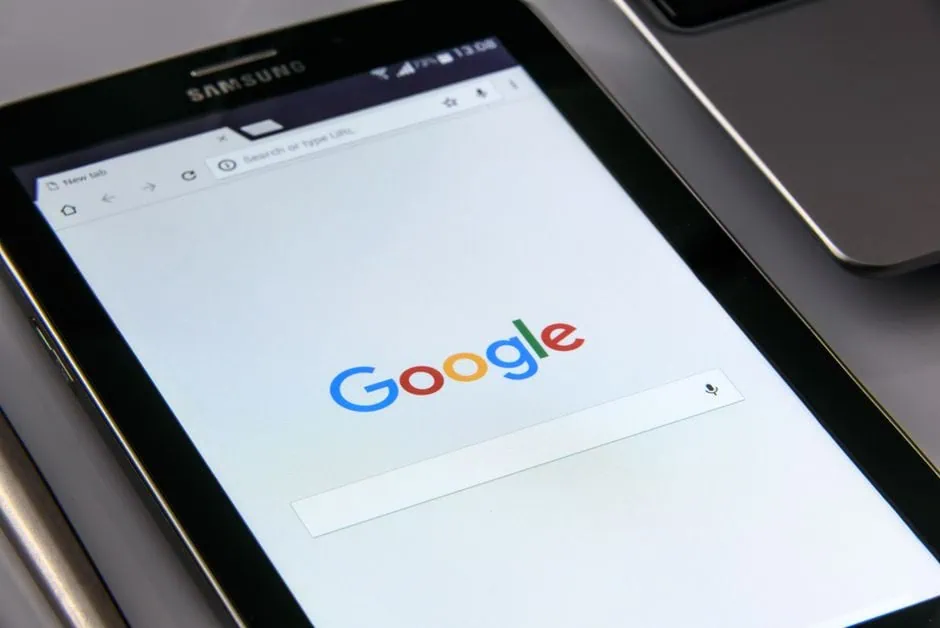 a samsung tablet displays the google search homepage, highlighting tools perfect for finding a local seo company. the device sits beside a laptop keyboard and a pen. market design team: define. structure. expand.
