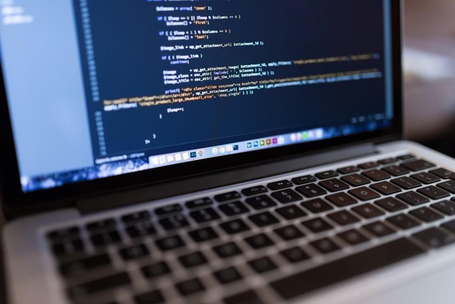a laptop screen displaying lines of computer code for responsive website design. market design team: define. structure. expand.