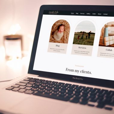 A MacBook Pro on a desk displays a webpage featuring three sections: "Blog" with a photo of a baby, "Services" with an image of a woman in a field, and "Collab" with a close-up of handmade products. The website highlights the artistry of Jennifer Duke Photography against star-shaped lights in the background. - Market Design Team: Define. Structure. Expand.